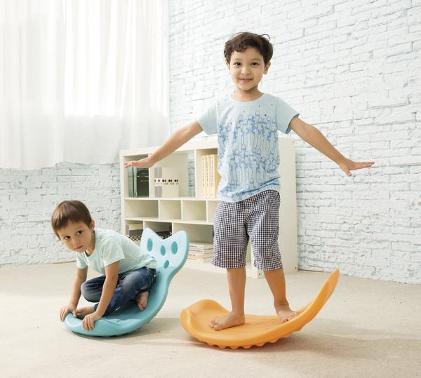 Zwei Jungen spielen mit bunten Wippbrettern in einem hellen, modernen Wohnzimmer.