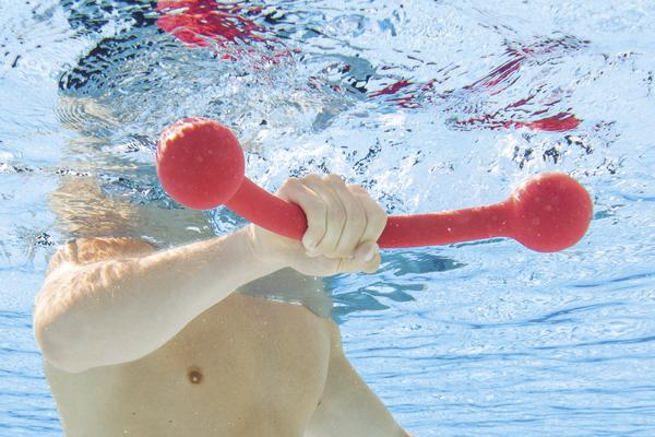 Unterwasseraufnahme eines Mannes, der mit rotem Aquafitness-Hantelgerät trainiert.