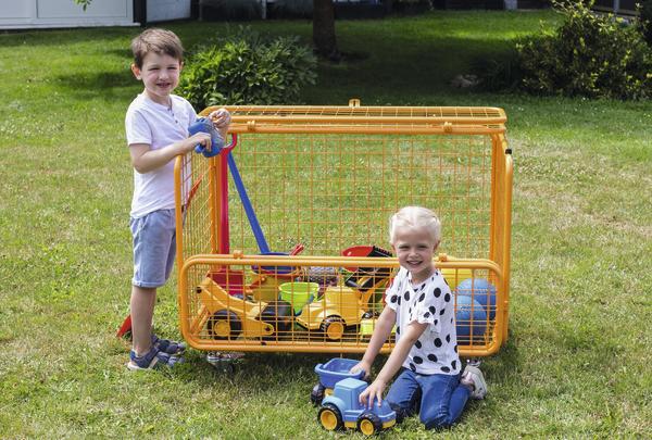 Zwei Kinder spielen mit buntem Spielzeug und Fahrzeugen auf grünem Rasen im Garten.