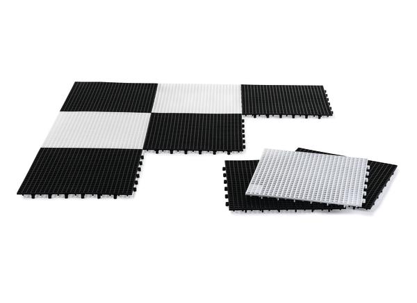 Schwarz-weiße modulare Bodenfliesen aus Kunststoff zum Zusammenstecken, teilweise verlegt.