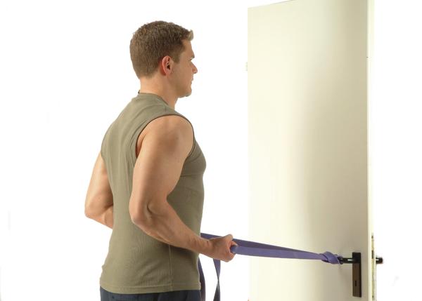Mann trainiert mit Widerstandsband an Türgriff für Arm- und Rückenmuskulatur.