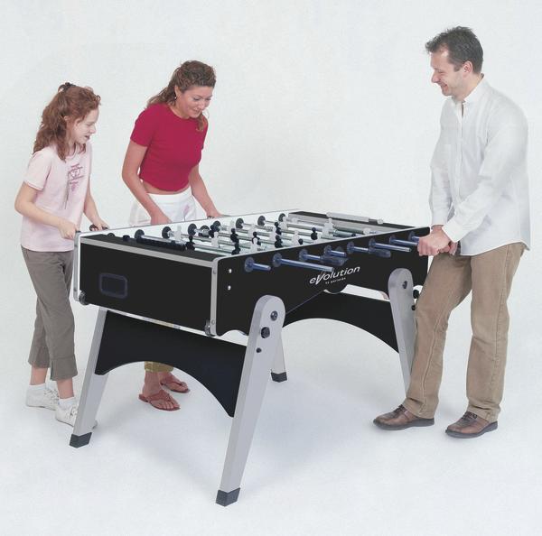 Familie spielt gemeinsam Tischkicker, Vater gegen Mutter und Tochter, weißer Hintergrund.