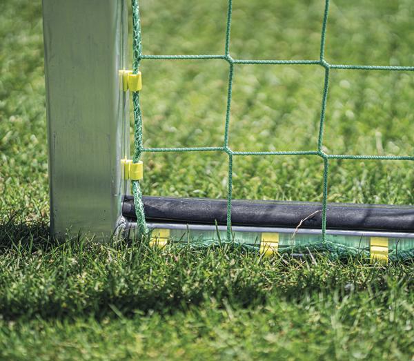 Nahaufnahme eines grünen Fußballtors mit Netz und Metallpfosten auf Rasen.
