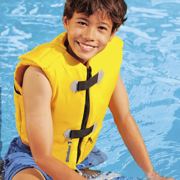 Junge mit gelber Schwimmweste lächelt im Schwimmbecken bei sonnigem Wetter.