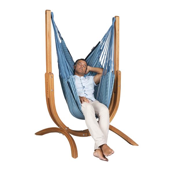 Mann entspannt in blauer Hängematte mit Holzgestell vor weißem Hintergrund.