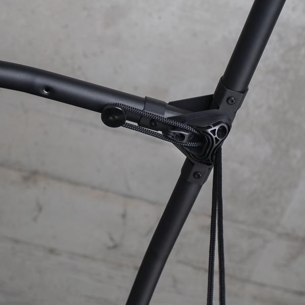 Schwarzer Hängesessel mit Zugseil und Befestigung vor grauer Wand.