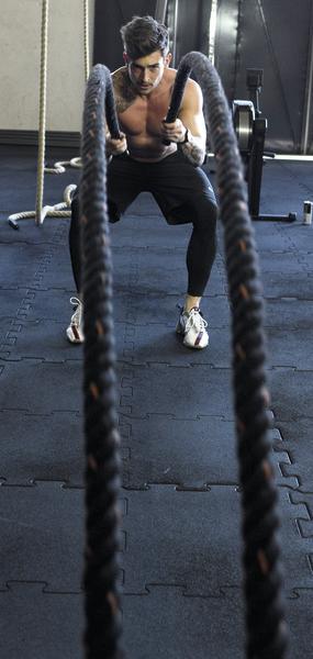 Mann trainiert mit Battle Ropes im Fitnessstudio für Kraft und Ausdauer.