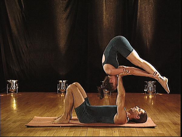 Paar übt Partnerakrobatik mit Balance und Kraft auf Yogamatte in Studio.