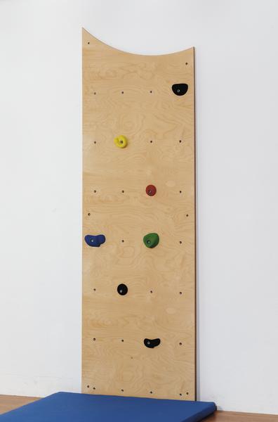 Kletterwand aus Holz mit bunten Griffen und blauer Matte für Indoor-Klettern.