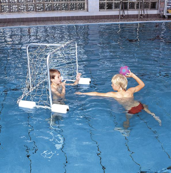 Zwei Jungen spielen Wasserball im Schwimmbad, einer hält den Ball, der andere verteidigt das Tor.