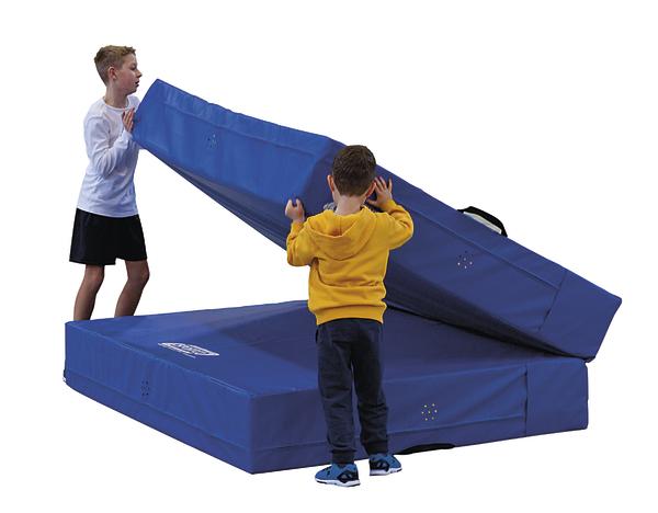 Zwei Jungen falten eine blaue Gymnastikmatte aus Schaumstoff zusammen.