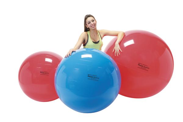 Frau mit drei großen Gymnastikbällen in Rot und Blau vor weißem Hintergrund.