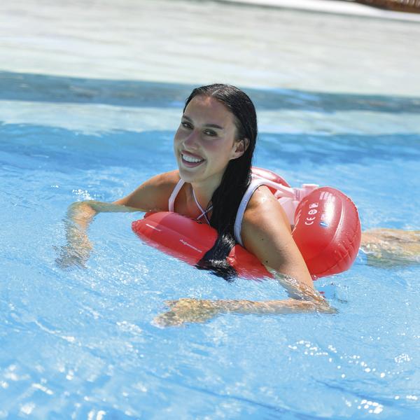Frau schwimmt im Pool mit einem rosa aufblasbaren Schwimmtrainer.