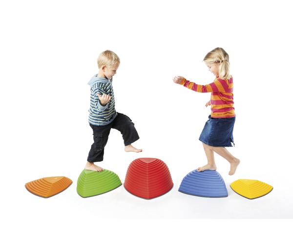 Kinder balancieren auf bunten Klettersteinen, spielerisch Gleichgewicht und Koordination trainierend.